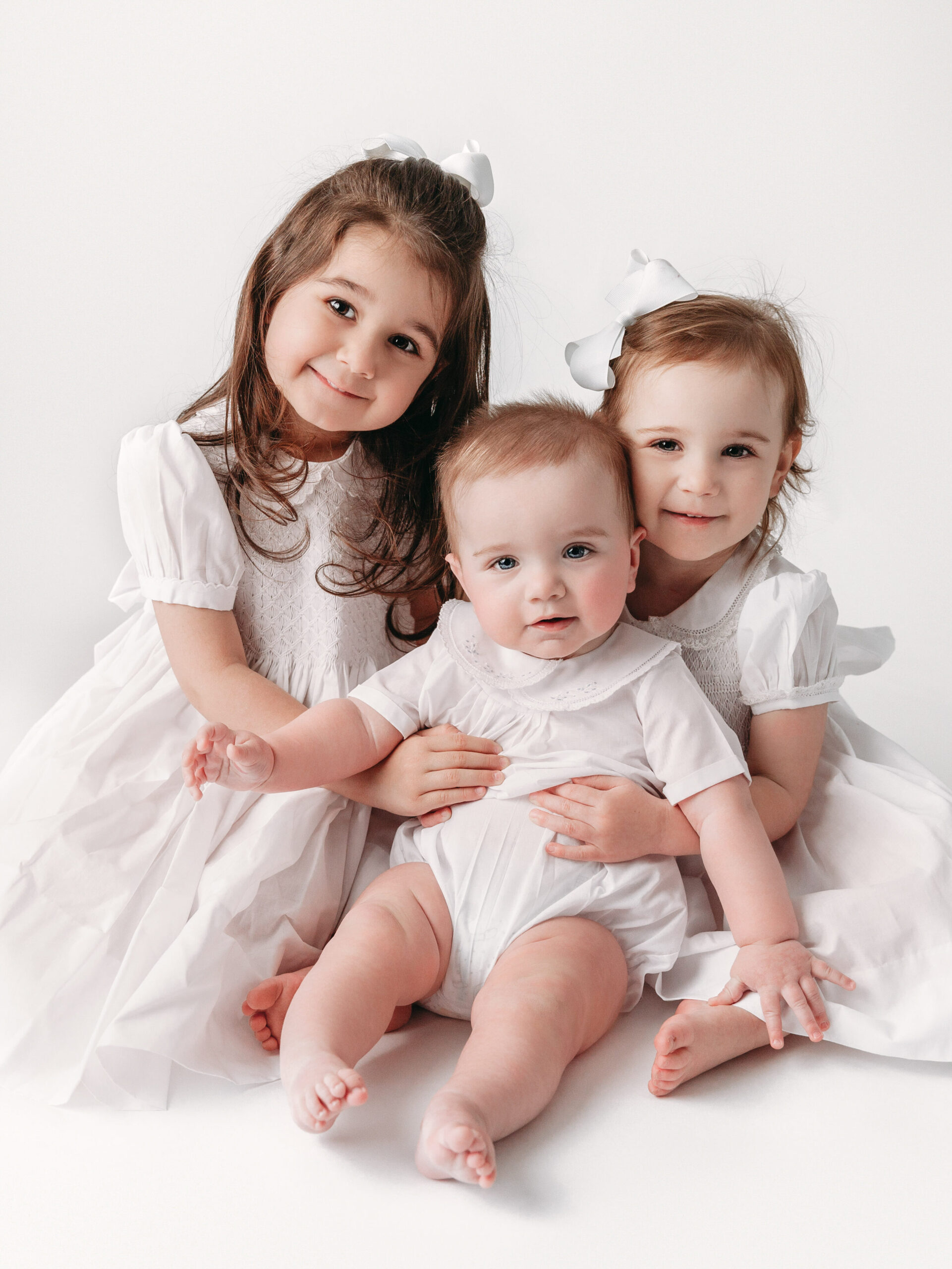 formal portrait of three siblings in white